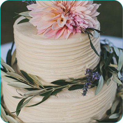 Two tier white wedding cake with flower topper