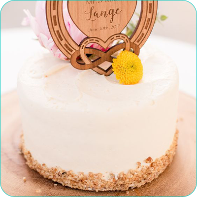 One tier white wedding cake with crumb coating along the bottom and wooden topper