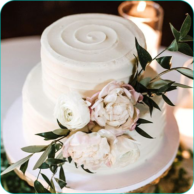 Two tier white wedding cake with peonies and swirl accent on top